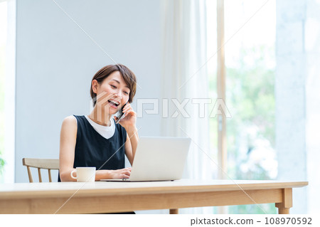 A woman teleworking in the living room. A woman teleworking in the living room. 108970592