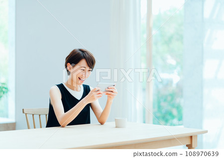A woman who operates a smartphone in the living room. 108970639