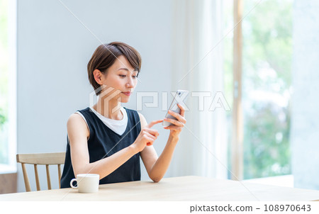 A woman who operates a smartphone in the living room. 108970643