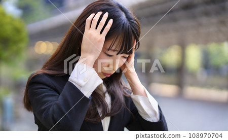 A woman holding her head in worry (AI generated image) 108970704