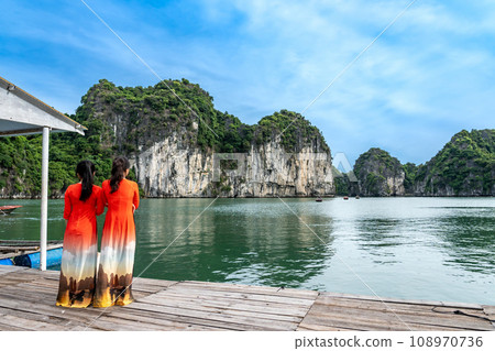A woman in a red ao dai waits for a tourist boat at a pearl farm in Ha Long Bay, Vietnam A woman in a red ao dai waits for a tourist boat at a pearl farm in Ha Long Bay, Vietnam 108970736