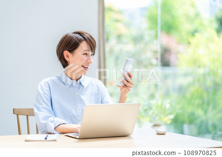 A woman teleworking in the living room. 108970825