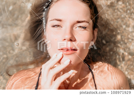 Woman summer travel sea. Happy tourist enjoy taking picture outdoors for memories. Woman traveler posing on the beach at sea surrounded by volcanic mountains, sharing travel adventure journey 108971929