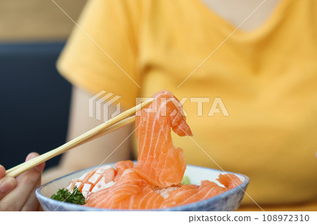 Asian woman eating salmon slice sashimi with rice in Japanese restaurant 108972310