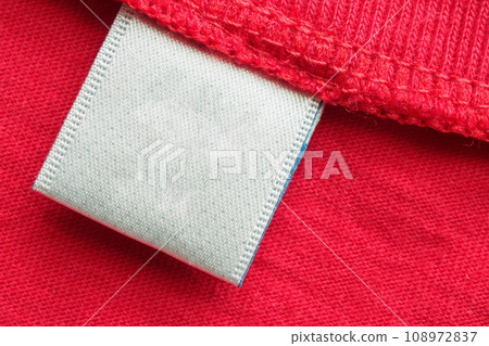 White blank laundry care clothes label on red cotton shirt background White blank laundry care clothes label on red cotton shirt background 108972837