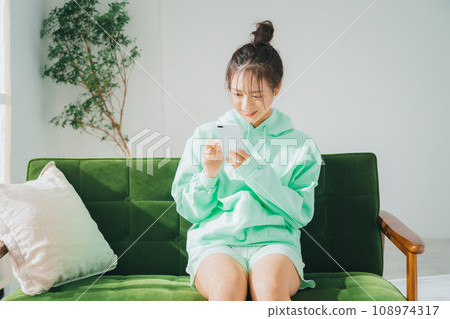 A woman using a smartphone in loungewear A woman using a smartphone in loungewear 108974317