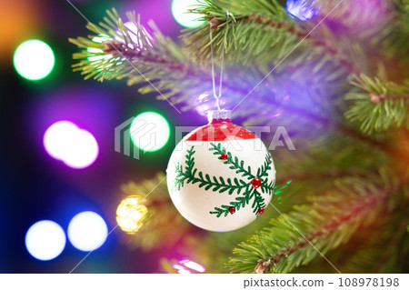 Christmas composition. Beautiful white ball on a Christmas tree closeup on a sparkling dark background Christmas composition. Beautiful white ball on a Christmas tree closeup on a sparkling dark background 108978198