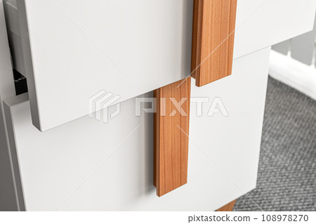 Stylish white office commode with wooden handles and legs with open empty drawers closeup view. Comfortable furniture for home and office furnishing Stylish white office commode with wooden handles and legs with open empty drawers closeup view. Comfortable furniture for home and office furnishing 108978270