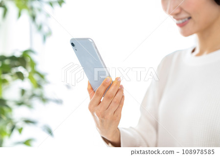 操作智能手機的中年婦女。 操作智能手機的中年婦女。 108978585