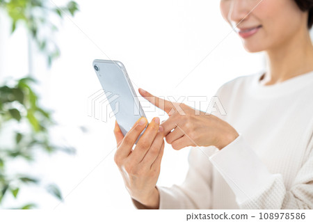 操作智能手機的中年婦女。 操作智能手機的中年婦女。 108978586