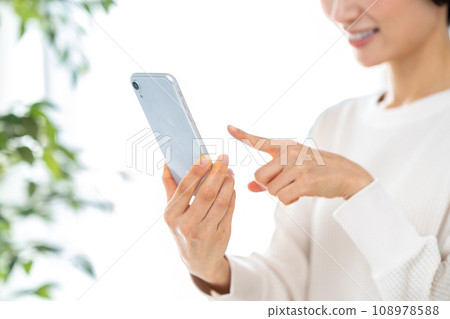 操作智能手機的中年婦女。 操作智能手機的中年婦女。 108978588
