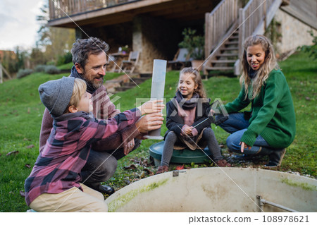 The family checks the water quality in the home wastewater treatment system. Concept of sustainable family living. 108978621