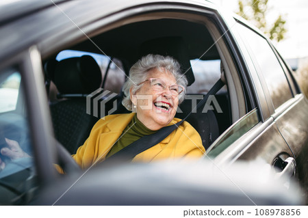 Happy senior woman driving car alone, enjoying car ride. Safe driving for elderly adults, older driver safety. 108978856