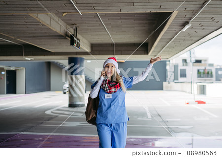 Portrait of beautiful nurse with christmas hat making call. Working in hospital on Christmas day, Christmas Eve. Female doctor working a Christmas shift and can't be with her family. 108980563