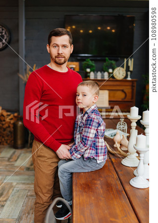 Dad with little son on wooden table in retro style country house room. Dad with little son on wooden table in retro style country house room. 108980598