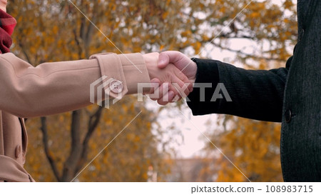 Man and woman work partners shake hands to sign contract at meeting in park Man and woman work partners shake hands to sign contract at meeting in park 108983715