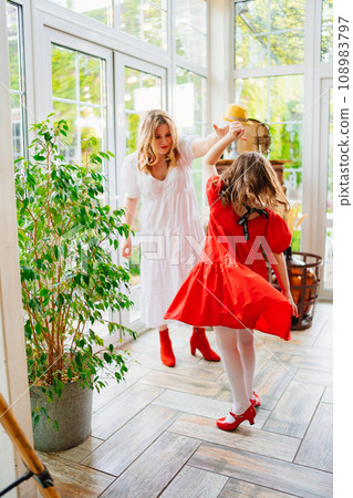 Mother and daughter in a room dancing in elegant dresses 108983797