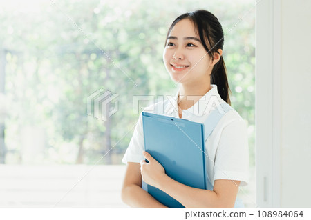 Young female caregiver standing by the window 108984064