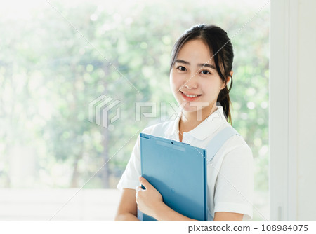 Young female caregiver standing by the window 108984075