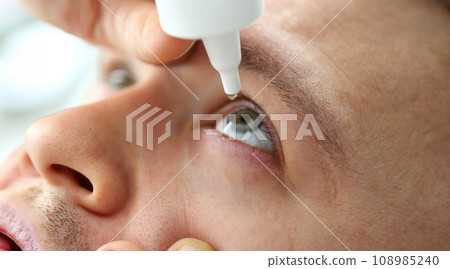 Man putting liquid drops in his eye solving vision problem Man putting liquid drops in his eye solving vision problem 108985240