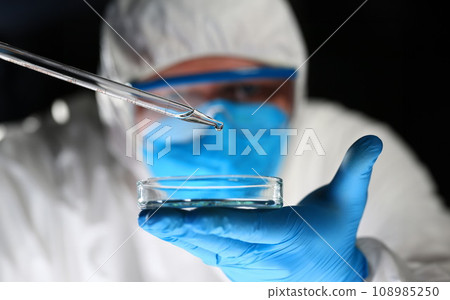 Male chemist look at microscope hold test tube 108985250