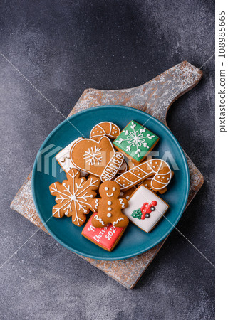 Beautiful delicious sweet winter Christmas gingerbread cookies on a gray textured background Beautiful delicious sweet winter Christmas gingerbread cookies on a gray textured background 108985665