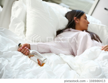 Young woman lying in bed deadly drunken Young woman lying in bed deadly drunken 108986413