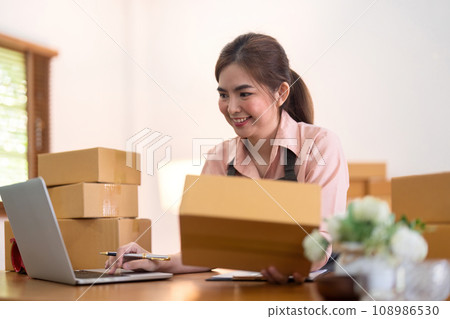 Young woman working online ecommerce shopping at her shop. Young woman sell prepare parcel box of product for deliver to customer. Online selling, ecommerce. Selling products online 108986530