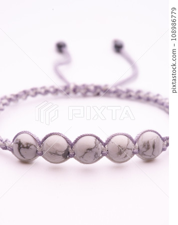 Tibetan Dzi bead. Cacholong Dzi bead Luck hook bracelet. Bracelet made of stones on hand from natural stone Cacholong. Bracelet made of natural stones. Handmade bracelets on black modern background. 108986779
