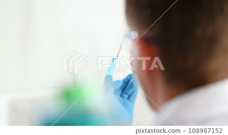 A male chemist holds test tube of glass A male chemist holds test tube of glass 108987152