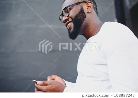 happy smiling hipster guy with cellphone enjoying time on publicity area happy smiling hipster guy with cellphone enjoying time on publicity area 108987245