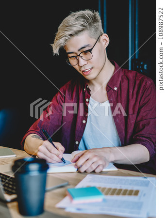 Japanese hipster student doing homework sitting at digital computer in modern coworking space Japanese hipster student doing homework sitting at digital computer in modern coworking space 108987522