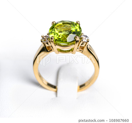 A vibrant peridot gemstone graces the center of a glossy, tarnish-resistant, yellow gold ring. The ring is accented with multiple pave-set  diamonds, sparkling exquisitely to complement the main stone 108987660