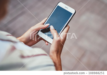 female blogger share publication updating feeds in profile while walking and holding mobile phone 108988251