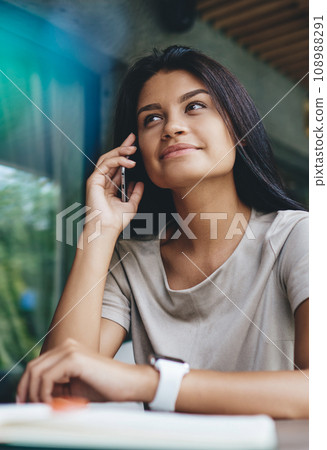 Pretty brunette woman having mobile phone conversation having free time at cafeteria, 108988291