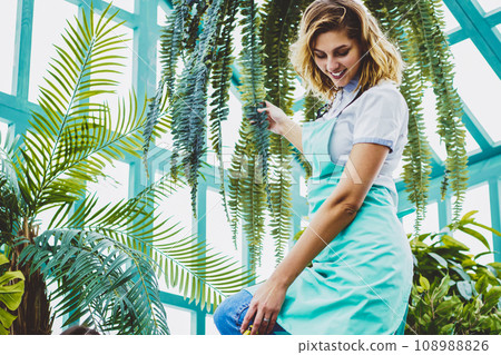 Cheerful female florists collaborating together in warmhouse taking care about green plants 108988826