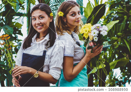 Half length portrait of successful gardeners dressed in casual aprons holding fresh flowers 108988930