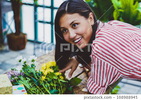 cheerful woman florist looking aside and laughing in orangery cheerful woman florist looking aside and laughing in orangery 108988945