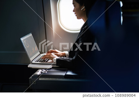 Successful Asian business woman, Business woman working in airplane cabin during flight on laptop computer 108989004