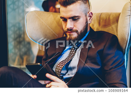 Entrepreneur in suit chatting online on telephone sitting on chair 108989164