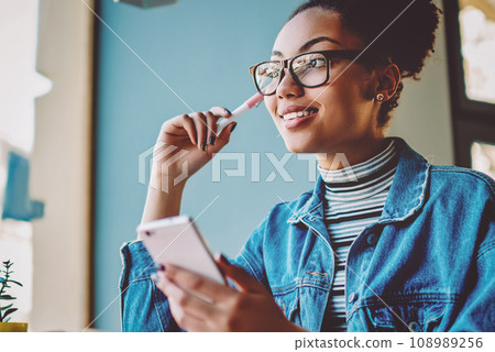 Positive contemplative hipster girl in stylish eyewear for vision correction looking away Positive contemplative hipster girl in stylish eyewear for vision correction looking away 108989256