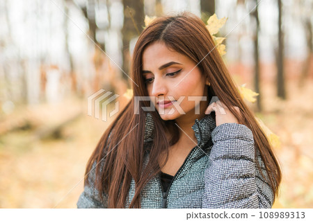 Close-up portrait of diversity young beautiful confident Indian Asian woman in fall outdoor. Happy and natural smiling female. Generation z and gen z youth concept 108989313