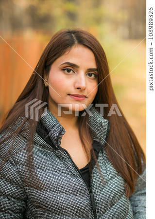 Close-up portrait of diversity young beautiful confident Indian Asian woman in fall outdoor. Happy and natural smiling female. Generation z and gen z youth concept Close-up portrait of diversity young beautiful confident Indian Asian woman in fall outdoor. Happy and natural smiling female. Generation z and gen z youth concept 108989326
