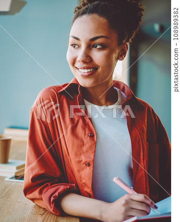 happy dark skinned woman holding textbook for education 108989382
