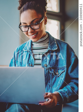 Positive dark skinned female student enjoying time for online shopping during leisure time for herself Positive dark skinned female student enjoying time for online shopping during leisure time for herself 108989411