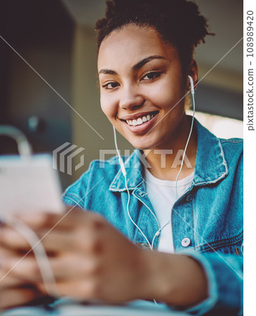 positive hipster girl enjoying music on radio station using mobile app positive hipster girl enjoying music on radio station using mobile app 108989420