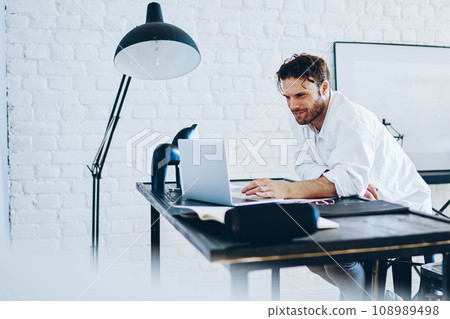 Serious male freelancer checking publication in blog on laptop computer working remotely Serious male freelancer checking publication in blog on laptop computer working remotely 108989498