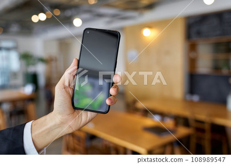 Hand of a businessman using a smartphone at a cafe Hand of a businessman using a smartphone at a cafe 108989547