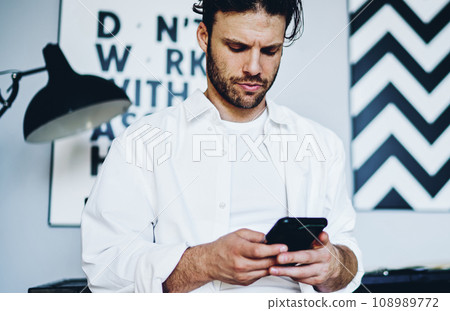 pensive hipster guy checking banking balance via mobile phone for making money transaction pensive hipster guy checking banking balance via mobile phone for making money transaction 108989772
