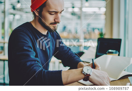 caucasian man in stylish apparel making notes of information in notepad for education 108989787